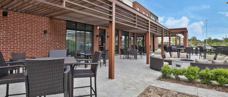 Un espace extérieur aménagé en patio, avec des murs en briques, des sièges abrités et un foyer.