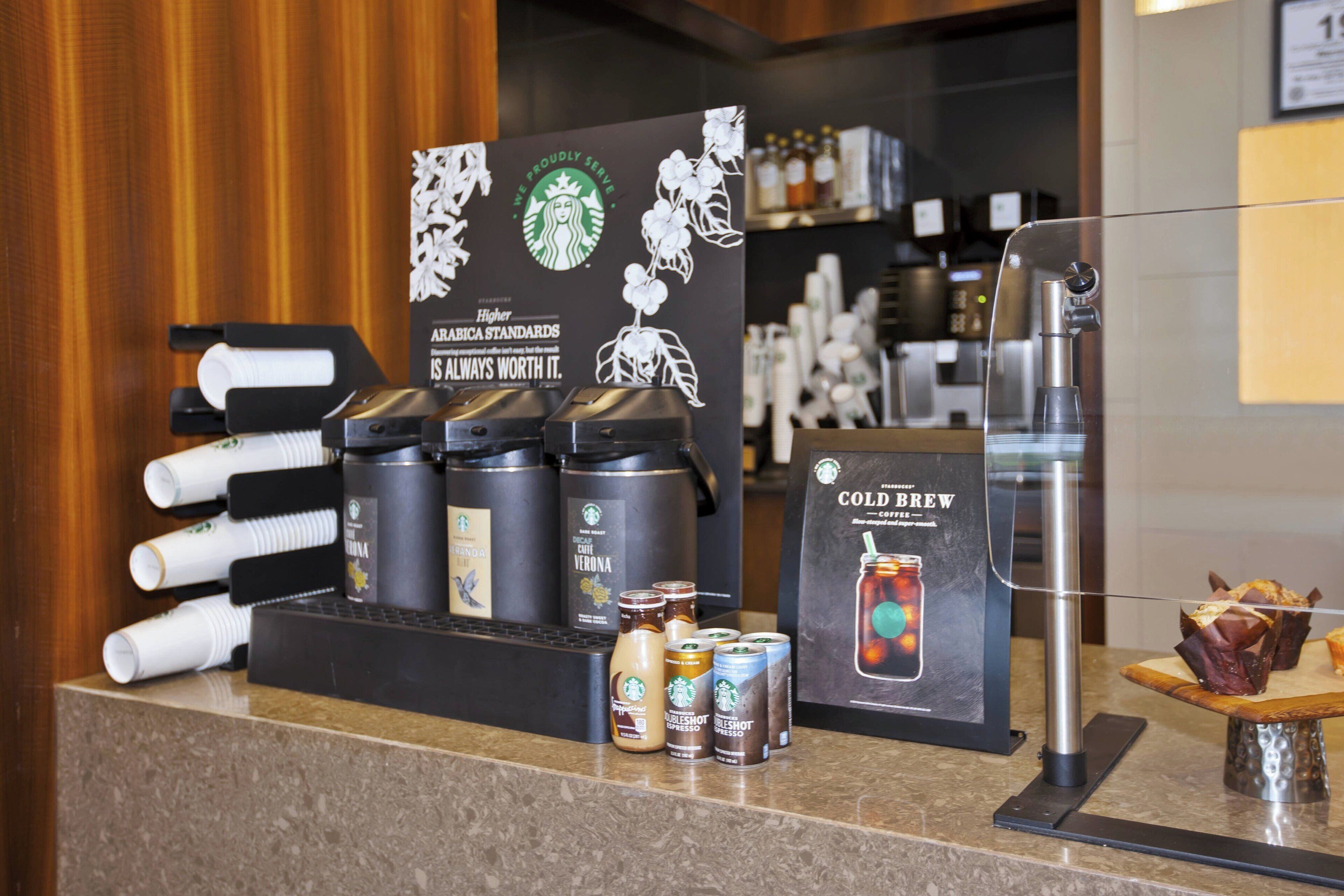 Una estación de café con distintos productos y un cartel que promociona el cold brew.