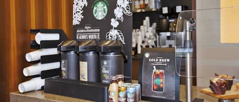 Una estación de café con distintos productos y un cartel que promociona el cold brew.