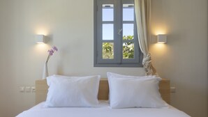 A neatly made bed with white linens and pillows, a vase with flowers, and two wall-mounted light fixtures. - Villa Anemos (Ampelas)