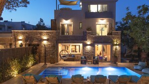Une maison moderne à deux étages, dotée d’une piscine, d’un espace extérieur aménagé et d’un patio bien éclairé.