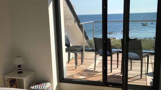 A bedroom with a large sliding glass door leading to an outdoor deck with chairs and a view of the sea. - Waterfront house Piriac sur mer (Piriac sur mer)