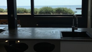 A kitchen with a large window overlooking a beach, a sink, and a chair. - Waterfront house Piriac sur mer (Piriac sur mer)