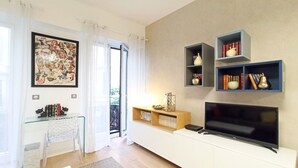 Ein modernes Wohnzimmer mit Flachbildfernseher, Glastisch und Bücherregal.