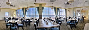 A large dining area with tables and chairs, large windows with curtains, and ceiling fans. - Oceanfront Suite w/ Incredible View + Official On-Site Rental Privileges (Myrtle Beach)