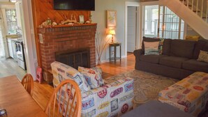 A cozy living room with a fireplace, a sofa, a coffee table, and a TV mounted on the wall. - Dennis Port beach home less than two tenths of a mile to Haigis public beach (Dennis Port)