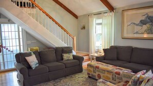 A living room with two sofas, a patterned rug, and a staircase. - Dennis Port beach home less than two tenths of a mile to Haigis public beach (Dennis Port)