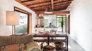 A cozy living room with a sofa, a dining table, and a kitchen in the background.