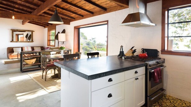 A kitchen with a central island, a stove, and a large window providing natural light.