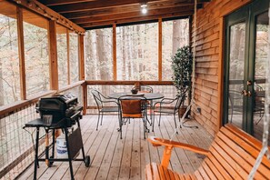 Une terrasse en bois avec un barbecue, une table et des chaises.