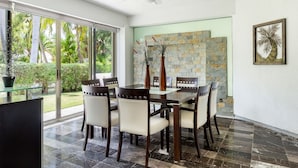 Un comedor con una mesa y sillas de vidrio, una pared de piedra y un ventilador de techo.