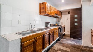 Una cocina con armarios de madera, un lavamanos de acero inoxidable y una estufa.