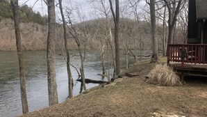Un chalet au bord du lac, doté d’une terrasse en bois et d’un mur en pierre.