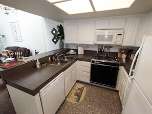 Kitchen area with microwave, oven, and dishwasher, featuring a sink and ample counter space.