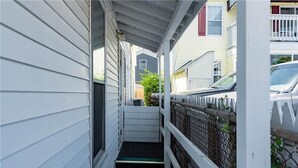 A narrow covered walkway with a metal fence, connecting two buildings. - Ocean Breezes at Salty Air Suites, Suite C – New Balcony, 3BR, walk to the Beach (Old Orchard Beach)