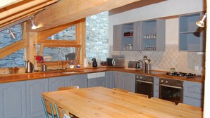 A kitchen with wooden cabinets, a large island, and a stone wall. - Spacious and comfortable chalet for 13 people - connected to Arcs 2000 in 20 minutes (Villaroger)