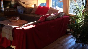 A cozy attic room with a wooden ceiling, a red sofa, a small table, and a Christmas tree. - Spacious and comfortable chalet for 13 people - connected to Arcs 2000 in 20 minutes (Villaroger)