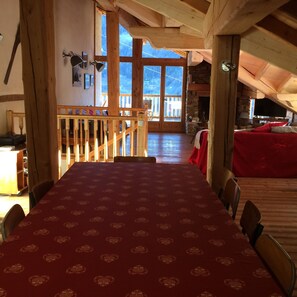 A dining area with a red tablecloth, wooden beams, and a view of the outdoors.