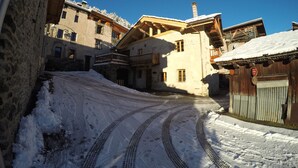 A snow-covered street with buildings featuring stone and wooden facades, a clear blue sky, and a 'No Parking' sign. - Spacious and comfortable chalet for 13 people - connected to Arcs 2000 in 20 minutes (Villaroger)