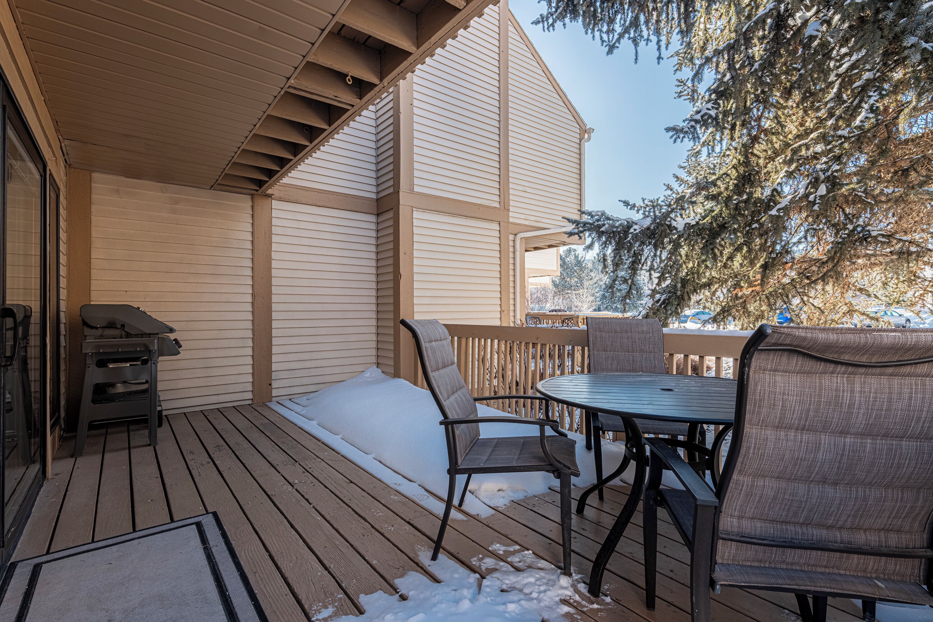 Une terrasse extérieure couverte, équipée d’un barbecue, de chaises et d’une table.