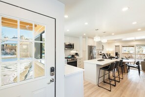 Une cuisine moderne avec des meubles blancs, des appareils en acier inoxydable et un grand îlot central doté de tabourets de bar.