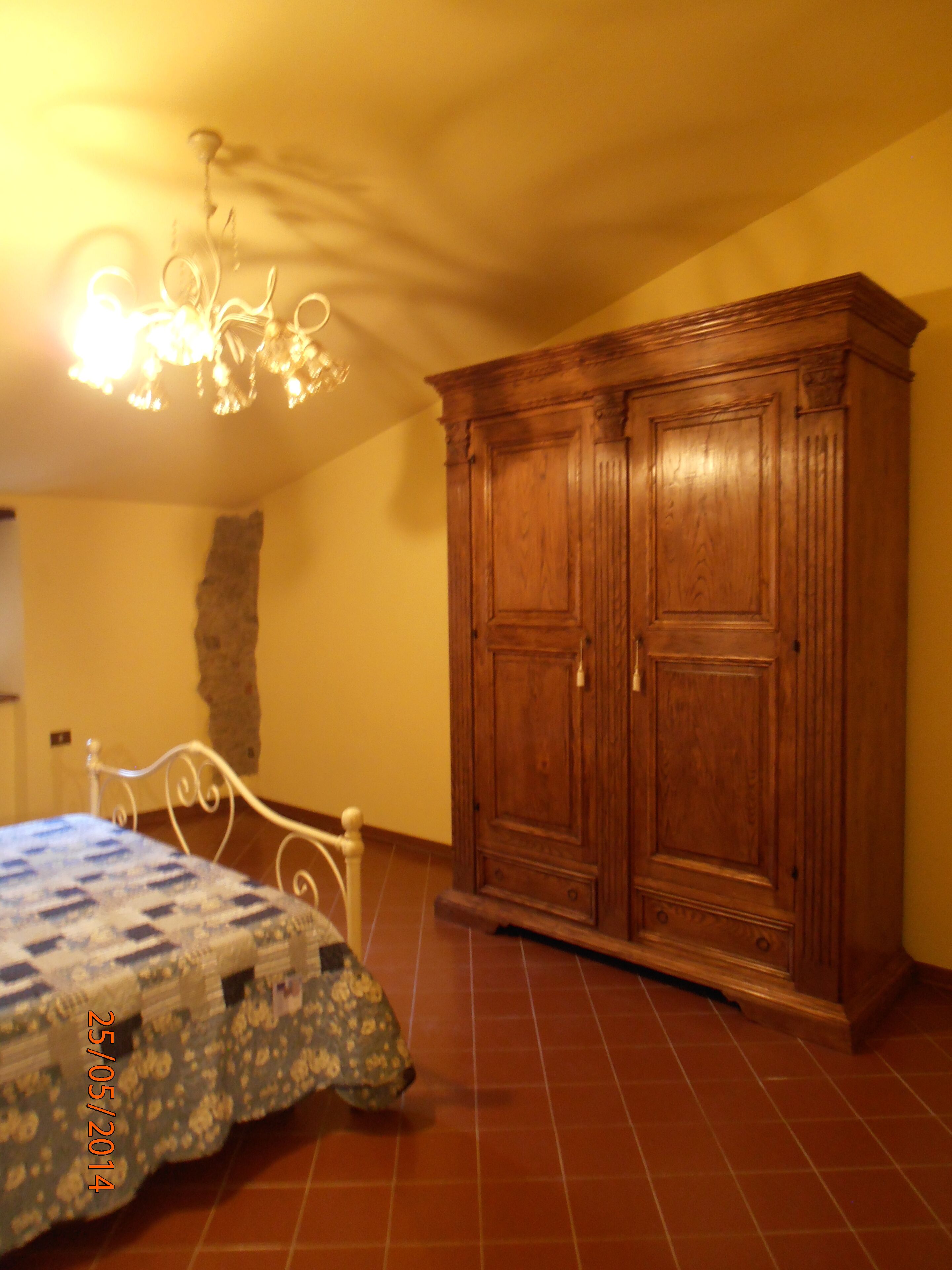 Une chambre à coucher avec un lit, une armoire en bois et un lustre.