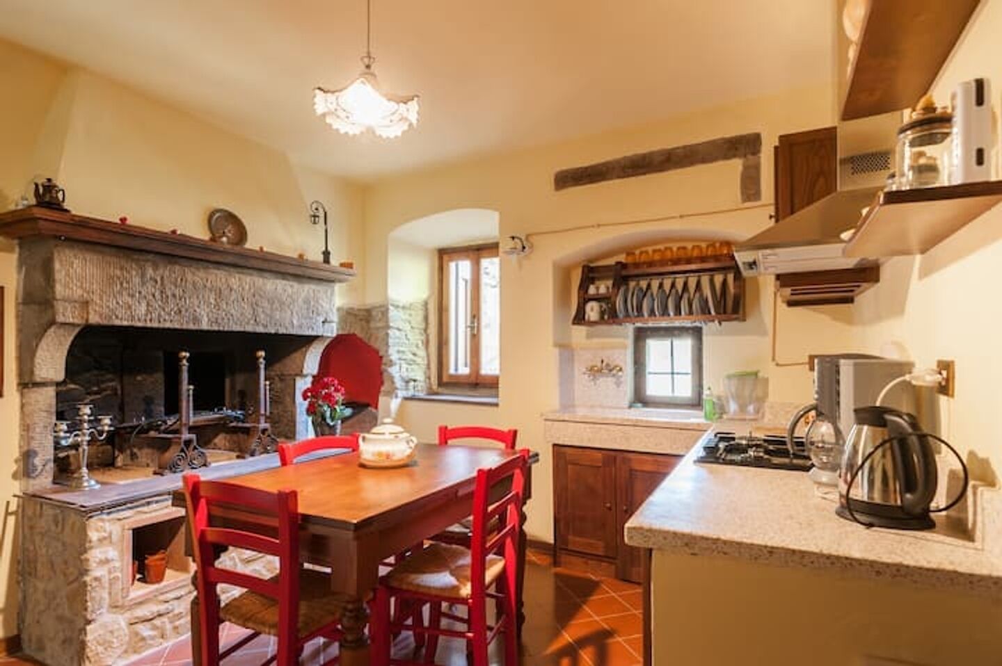 Una cocina con chimenea de piedra, una mesa de comedor con sillas y una encimera moderna.