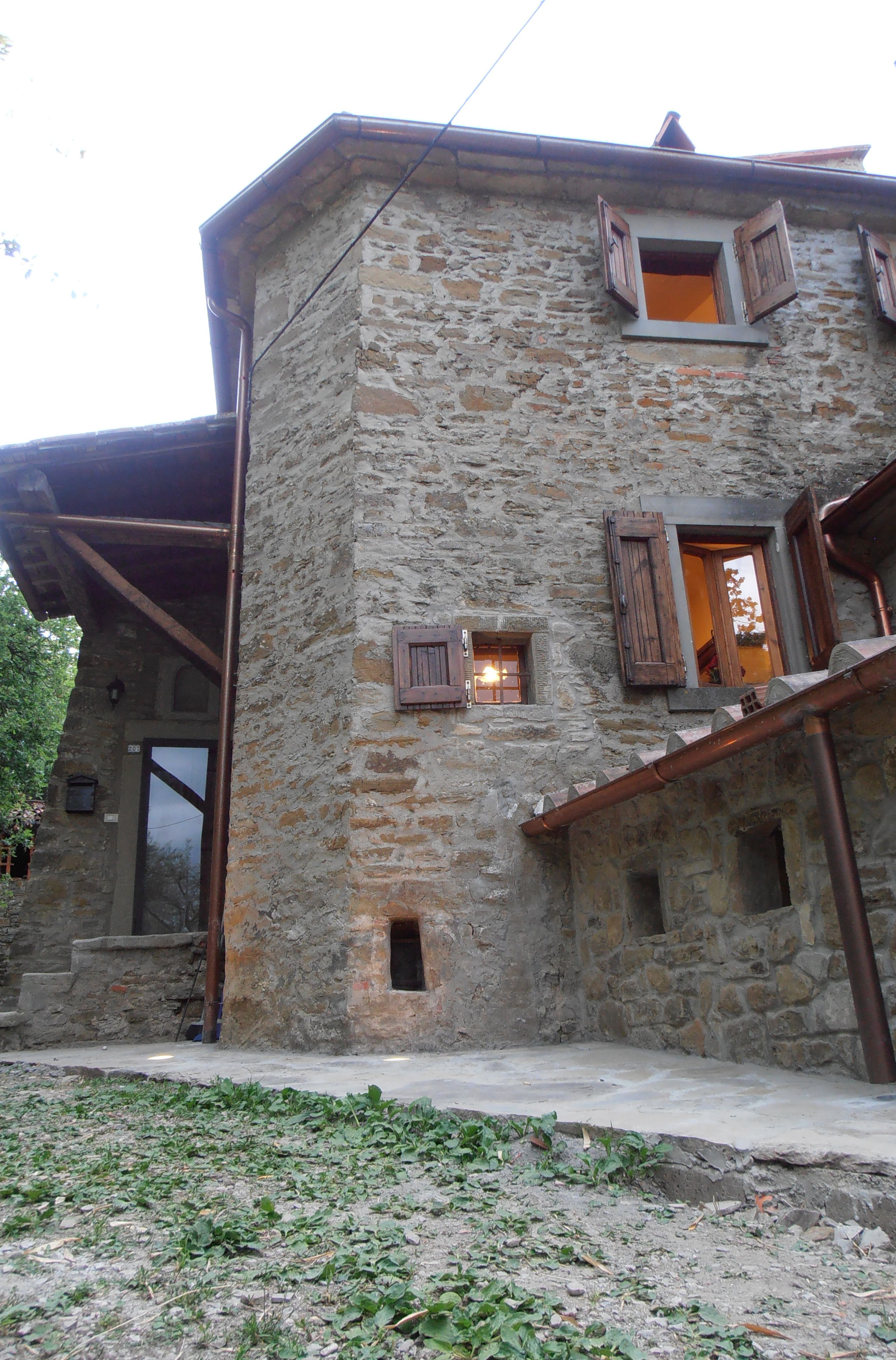 Un edificio in pietra con diverse finestre e una porta in legno.