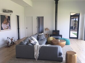 Relax in this stylish living room with a large sofa, decorative horse sculpture, and a wood-burning stove.