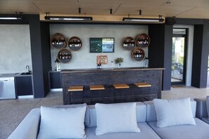 Relax in a contemporary space with a comfortable seating area and a stylish bar featuring a wooden countertop and artwork.