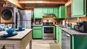 Una cocina moderna con armarios verdes, electrodomésticos de acero inoxidable y techo de madera.