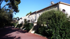 A row of traditional Mediterranean-style buildings with uniform architecture, a paved pathway, and lush greenery. - ST RAFAEL-BOULOURIS, seaside, great appartment 2room, ground floor (St. Rafaël - Boulouris)