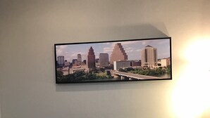A black leather sofa with three cushions and a framed cityscape picture on the wall. - Your Retreat in Austin - Relax & enjoy free Netflix movies Pet Stays for Free ! (Austin)