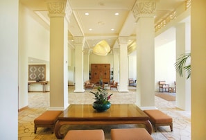 A spacious lobby with a central table, seating, and a decorative ceiling light.