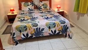 Une chambre à coucher comprenant un lit, deux tables de chevet, une commode, une moustiquaire et une œuvre d’art accrochée au mur.