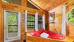 A wooden cabin with a red bathtub, wooden walls, and a window with blinds. - SR•Cozy Mountain Cabin• Private Hot Tub•1.5 Miles to Dollywood• Walk to the Pool (Sevierville)