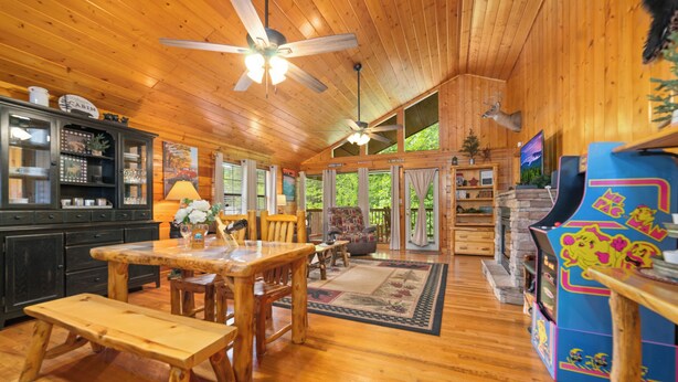 A wooden cabin interior with a dining area, a fireplace, and a television. - SR•Cozy Mountain Cabin• Private Hot Tub•1.5 Miles to Dollywood• Walk to the Pool (Sevierville)