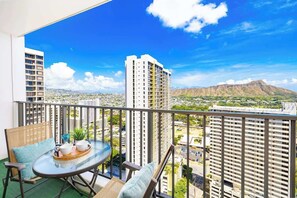 Un balcon avec une table et des chaises, offrant une vue sur la ville et les montagnes.