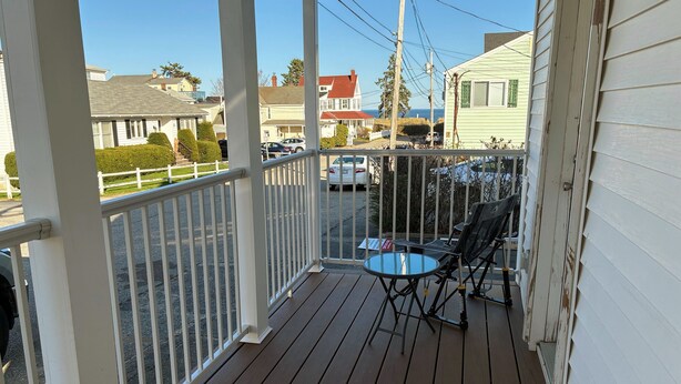 A wooden deck with a glass table and chairs, overlooking a street with parked cars and houses. - Salty Air Suites, B:  Easy to walk in, One level, 3 beds, ocean views. (Old Orchard Beach)