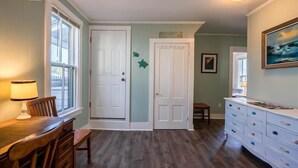 A room with a wooden dining table, two white doors, a white dresser, and a painting on the wall. - Salty Air Suites, B:  Easy to walk in, One level, 3 beds, ocean views. (Old Orchard Beach)