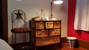 Ein Zimmer mit einem Korbschrank, einer sternförmigen Metalldeko, einer Lampe und einem weißen Vorhang.
