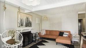 A living room with a fireplace, a hanging chair, a sofa, and a patterned rug.