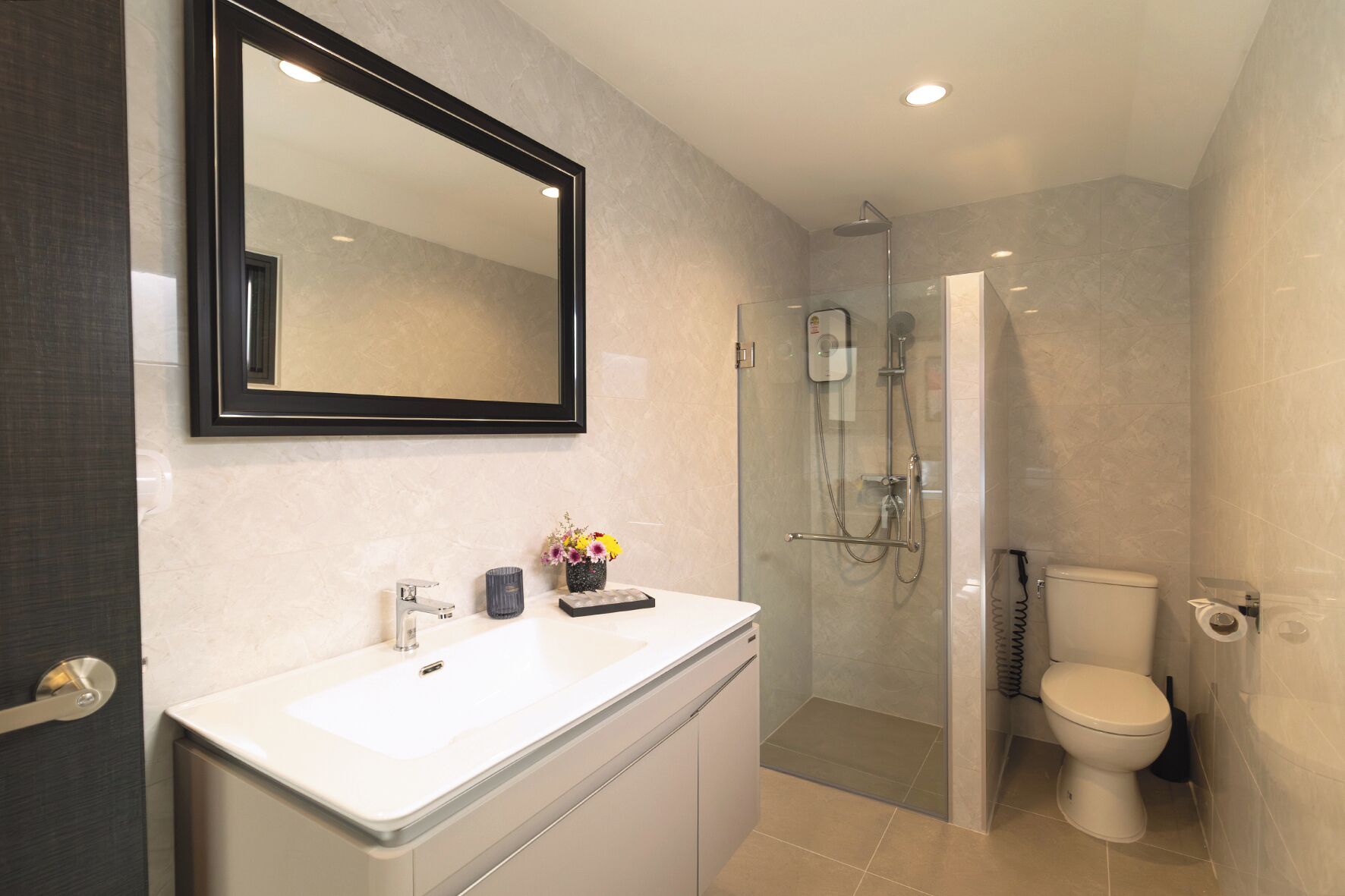 Un baño moderno con un espejo grande, un lavamanos blanco, cabina de ducha con mampara de vidrio y un inodoro.