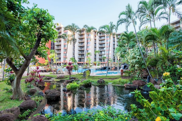 A resort with a pool, lush greenery, and a building with balconies.