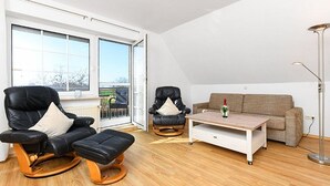 Un salon moderne avec un canapé en cuir noir, une table basse en bois et un canapé beige.