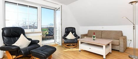 Una sala moderna con un sofá de cuero negro, una mesa de centro de madera y un sofá color beige.