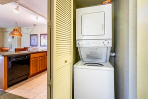 Cocina compacta con armarios de madera, lavavajillas y lavadora y secadora integradas.