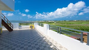 A terrace with a view of the sea and greenery, a staircase, and a yellow air conditioning unit. - 917 Homestay (Magong)
