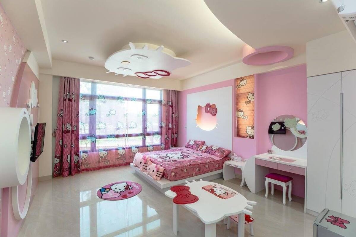 A pink-themed bedroom with a bed, desk, and vanity.