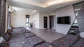 A modern hotel room with a long sofa, a desk, and a TV mounted on the wall. - 917 Homestay (Magong)